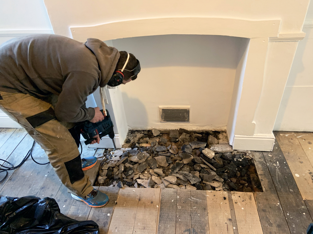 Team member Tom drills out the old hearth